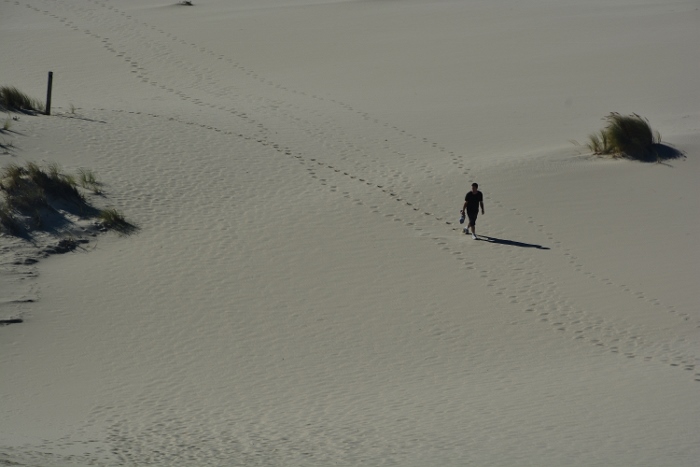 man walking sandy dunes